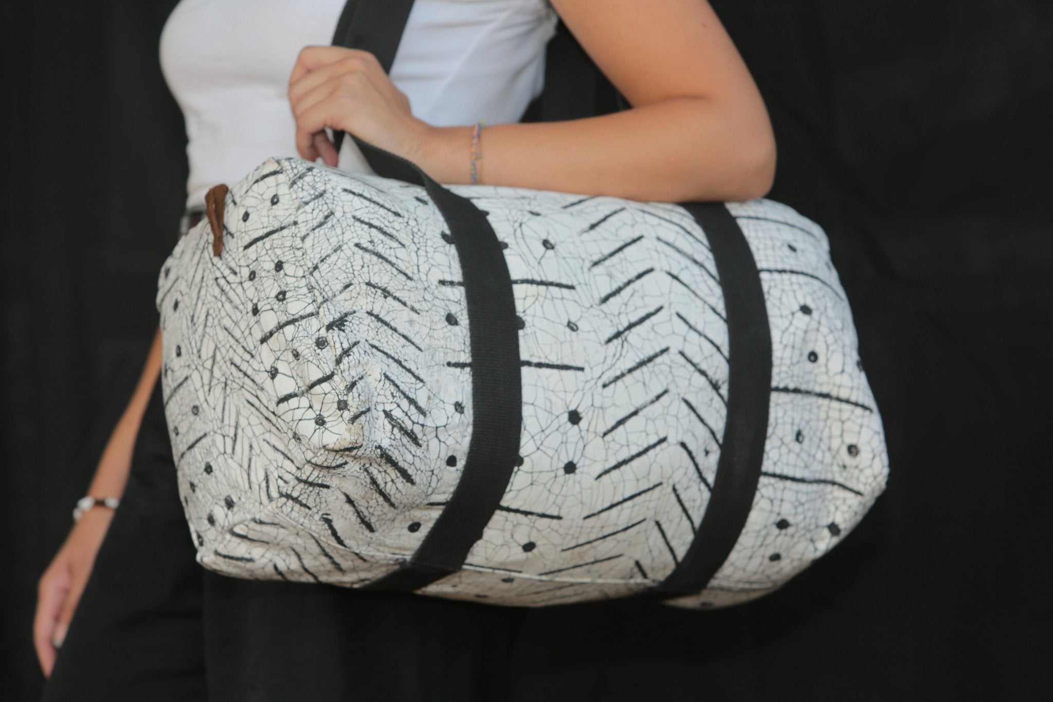 Hand-painted weekend bag in white with black straps, destined to bring stylish elegance on your trips away.